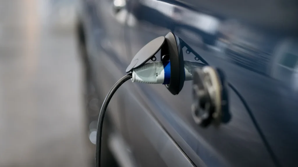 Cable conectado a la toma de recarga de un coche eléctrico azul